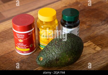 Verschiedene Flaschen Vitamintabletten und eine frische Avocadobirne Von M&S for Healthy living Lifestyle UK Stockfoto