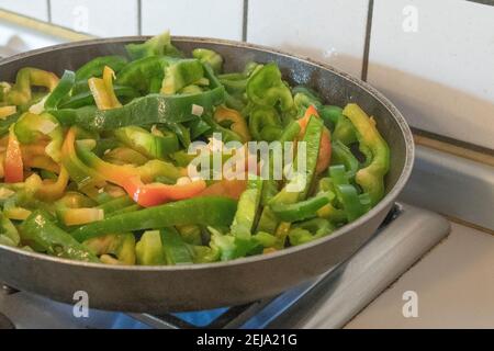 Grüner Pfeffer Kochen in einer Pfanne auf einem Gas-Kochfeld Stockfoto