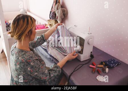 Das Mädchen ist mit dem Nähen zu Hause auf a beschäftigt Nähmaschine Stockfoto
