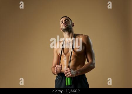 Taille up Porträt von liebenswert bärtigen kaukasischen Sportler mit muskulösen Körperpose und Blick auf die Kamera im Innenbereich Stockfoto