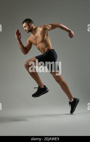 In voller Länge Seitenansicht Porträt des schönen starken kaukasischen Sportler Mit stout Körper tun Joggen im Raum drinnen Schwarze Shorts Stockfoto