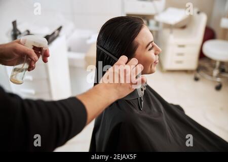 Professionelle Friseur Glättung der lächelnden Frau Haare Stockfoto