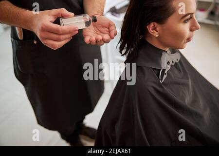 Friseur Anwendung einer Haarlotion auf seiner Handfläche Stockfoto
