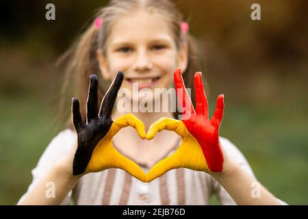 Kinder Hände in Belgien Flagge Farbe gemalt zeigen Symbol des Herzens und Liebe Geste auf Natur Hintergrund. Konzentrieren Sie sich auf die Hände Stockfoto