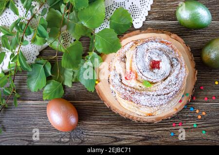 Süßer Osterkuchen, bemalte Eier, grüne Zweige auf einem Holztisch. Draufsicht. Stockfoto