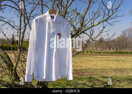 Weißes Hemd hängend draußen mit tricolor Rosette Symbol der ungarischen Nationalfeiertag 15th märz . Stockfoto