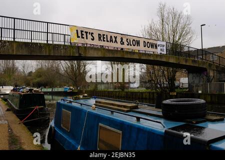 HACKNEY, LONDON - 22nd. FEBRUAR 2021: Ein Spruchband mit der Aufschrift "Lass uns entspannen und langsamer werden, Halt HS2" entlang einer Fußgängerbrücke über den Fluss lea in der Nähe von Hackney Marshes Stockfoto