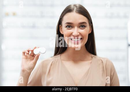 Glückliche Dame hält Kontaktlinsen in Optik-Shop Stockfoto