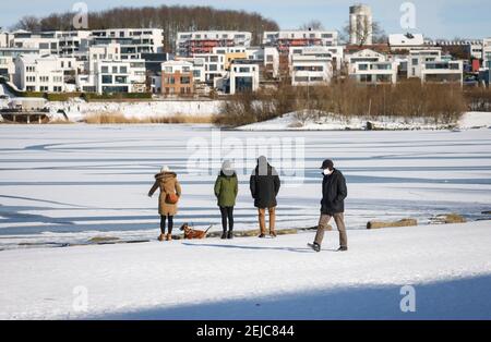 Dortmund, Ruhrgebiet, Nordrhein-Westfalen, Deutschland - Spaziergänger am Phoenix See im Winter in Eis und Schnee in Zeiten der Corona Pandemie mit Maske, hinten Stockfoto