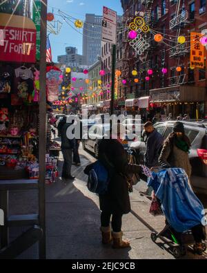 NEW YORK CITY, VEREINIGTE STAATEN - Jan 05, 2021: Menschen stehen in Chinatown Hauptstraße, die bunte Laternen im Hintergrund hängen hat. Stockfoto