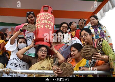 Kalkutta, Indien. Februar 2021, 22nd. Der Aktivist des All India Trinamool Congress (TMC) Mahila Morcha (Women Wing) hält eine Dummy-Kochgasflasche und Ghutes oder Kuhmist-Kuchen, um bei der Sit-in-Demonstration gegen steigende Kraftstoffpreise im ganzen Land zu protestieren. (Foto von Biswarup Ganguly/Pacific Press) Quelle: Pacific Press Media Production Corp./Alamy Live News Stockfoto