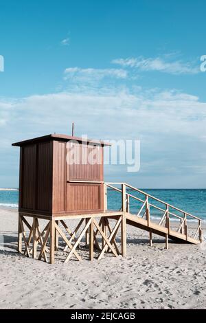 Detail eines hölzernen Rettungsschwimmerturms in einem einsamen Strand nahe der Küste, mit dem Ozean im Hintergrund Stockfoto