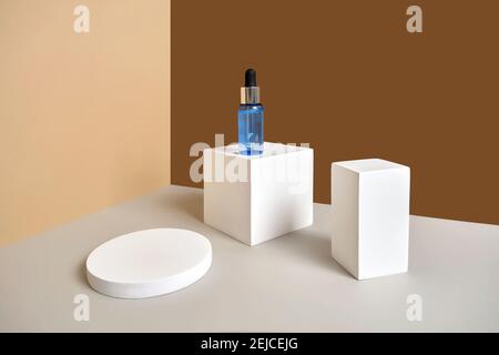 Flasche Serum steht auf weißem runden und rechteckigen Podium mit Zweigen von getrockneten Blumen. Wabisabi-Stil, Erdton. Hautpflege kosmetische Zusammensetzung Stockfoto