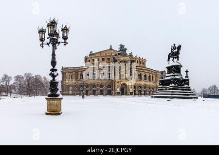 Das Opernhaus Semperoper und das König Johann Denkmal im Winter, der Theaterplatz im Schnee bedeckt. Stockfoto