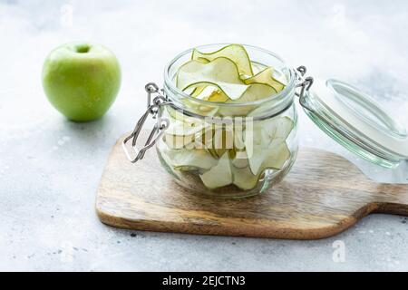 Offenes Glas mit Apfelchips auf Holzbrett Stockfoto