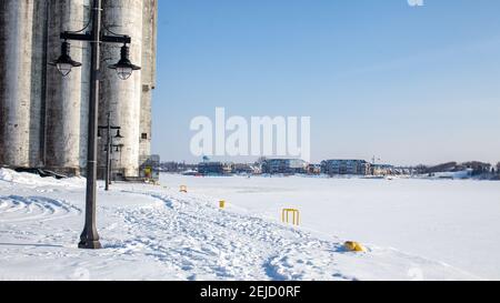 Ein Blick auf den Collingwood Harbour im Winter, mit dem Hafen eingefroren, Blick in die Stadt vom Pier. Eisangeln Hütten können von der gesehen werden Stockfoto