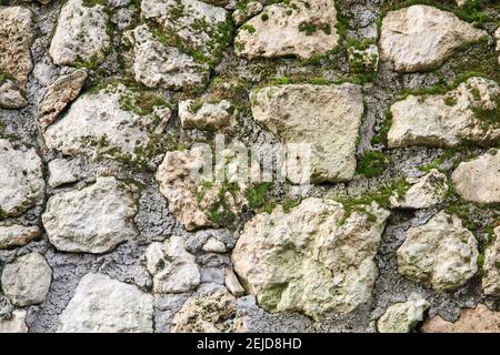 Hintergrund, Textur - moosig raues Mauerwerk aus natürlichem Rohstein Stockfoto
