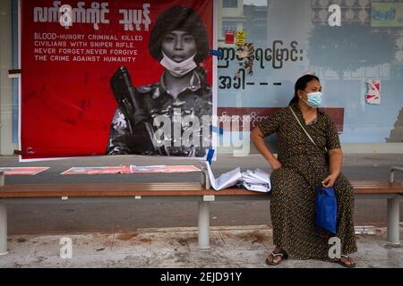 Ein Protestler an einer Bushaltestelle sitzt neben einem Demonstrationsplakat während des Protestes gegen den Militärputsch in Yangon. Das Militär von Myanmar nahm am 01. Februar 2021 die staatliche Beraterin von Myanmar Aung San Suu Kyi fest und erklärte den Ausnahmezustand, während sie die Macht im Land für ein Jahr ergattete, nachdem sie die Wahl gegen die National League for Democracy (NLD) verloren hatte. Stockfoto