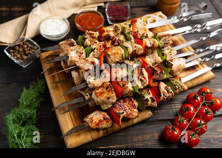 Pute oder Huhn Schisch Kebab auf Metallspieße mit Pfeffer Tomaten und Zwiebel auf rustikalem Holztisch Hintergrund Stockfoto