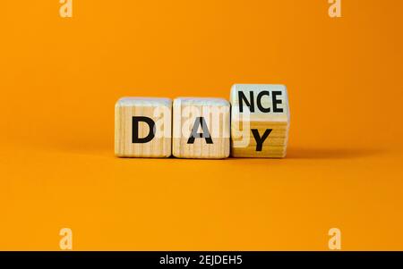 Symbol für den Internationalen Tanztag. Drehte den Würfel mit den Worten 'Tanztag'. Schöner orangefarbener Tisch, orangefarbener Hintergrund, Kopierbereich. Internationaler Tanztag Stockfoto