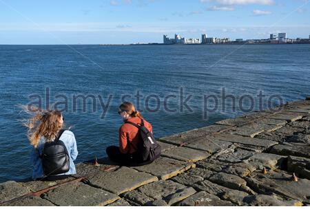 Edinburgh, Schottland, Großbritannien. Februar 2021, 22th. Menschen genießen Granton Hafen und Wellenbrecher an einem kalten und sonnigen Nachmittag. Blick auf die moderne Entwicklung in Leith. Kredit: Craig Brown/Alamy Live Nachrichten Stockfoto