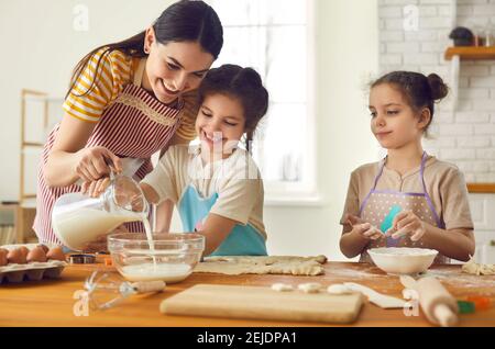 Glückliche Mutter und Töchter mischen Zutaten für Kuchen, Kuchen oder Plätzchen Teig zusammen Stockfoto