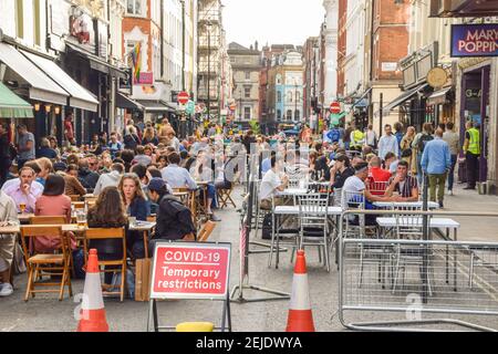 Menschen in Restaurants und Bars in Old Compton Street, Soho. Die temporären Straßensitze im Freien wurden eingeführt, um die soziale Distanzierung während der Coronavirus-Pandemie zu erleichtern. London, Großbritannien August 2020. Stockfoto