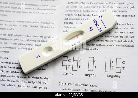 Corona Schnelltest: Testkassette und Packungsbeilage mit der Gebrauchsanweisung zeigt es einen negativen Covid-19 Antigen Schnelltest der chinesischen Firma Joinstar Biomedical mit einer Speichelprobe. --- Corona-Schnelltest: Testkassette und Beipackzettel mit der Gebrauchsanweisung, sie zeigt einen durch eine Speichelprobe vorgegebenen negativen Covid-19 Antigen-Schnelltest der chinesischen Firma Joinstar Biomedical. Stockfoto