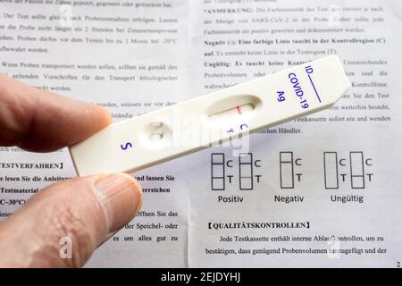 Corona Schnelltest: Testkassette und Packungsbeilage mit der Gebrauchsanweisung zeigt es einen negativen Covid-19 Antigen Schnelltest der chinesischen Firma Joinstar Biomedical mit einer Speichelprobe. --- Corona-Schnelltest: Testkassette und Beipackzettel mit der Gebrauchsanweisung, sie zeigt einen durch eine Speichelprobe vorgegebenen negativen Covid-19 Antigen-Schnelltest der chinesischen Firma Joinstar Biomedical. Stockfoto