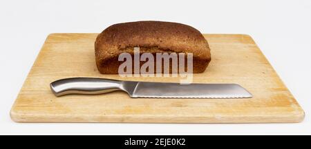 Ein Laib gesunden, frisch gebackenen Vollkornbrot sitzt auf einem Schneidebrett mit Messer bereit geschnitten werden. Stockfoto