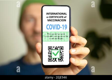 Die Männer halten ein Smartphone mit elektronischem Coronavirus-Impfpass oder Impfpass für Reisende. COVID-19 Immunität e-Pass mobile App für internationale Reisen. Hochwertige Fotos Stockfoto