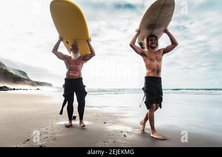 Glückliche Freunde gemeinsam auf dem tropischen Ozean surfen - Sportliche Menschen haben Spaß während des Urlaubs Surf Day - Extreme Sport Lifestyle Konzept Stockfoto