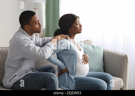 Schwarze schwangere Frau mit Rückenschmerzen zu Hause Stockfoto