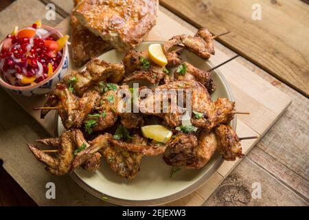 Britische Hähnchenflügel, die in Chili-Gewürzen und Zatar-Gewürzen mariniert wurden, bevor sie auf Bambus-Kebab-Spieße gespiebt und dann gegrillt wurden. Se Stockfoto