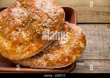 Hausgemachtes türkisches Pide-Brot, das mit Eigelb und Sesam glasiert wurde, auf einem hölzernen Hintergrund. England GB Stockfoto