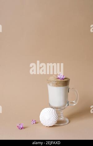 Schöner Dalgon Kaffee Drink mit Schaum in einer transparenten Tasse und Marshmallows auf einem beigen Hintergrund. Speicherplatz kopieren Stockfoto