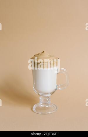 Schöner Dalgon Drink Kaffee mit Schaum in einem transparenten Becher auf beigem Hintergrund Stockfoto