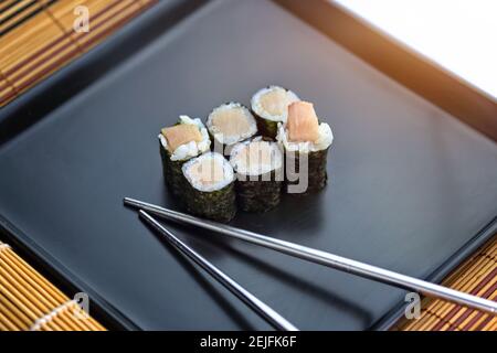 Köstliches Sushi-Set auf einem Teller mit Essstäbchen Stockfoto