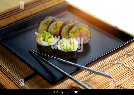 Sushi-Rolle auf einem schwarzen Teller bereit, serviert werden Stockfoto