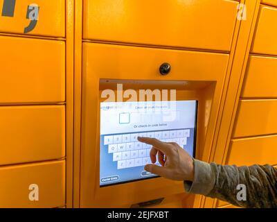 Mann, der Amazon locker im Einkaufszentrum verwendet, orangefarbene Abholstelle für Versandartikel mit dem Logo der Marke Amazon. Mobile Fotografie. Lyon, Frankreich - F. Stockfoto