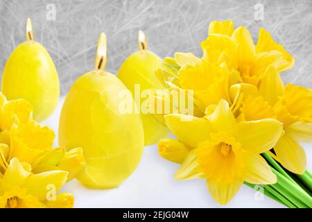 Gelbe Osterdekoration mit Kerzen und Narzissen Stockfoto