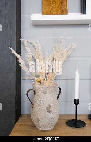 Antike Keramikvase mit getrockneten Blumen und einer Kerze in Die Einrichtung des Hauses Stockfoto