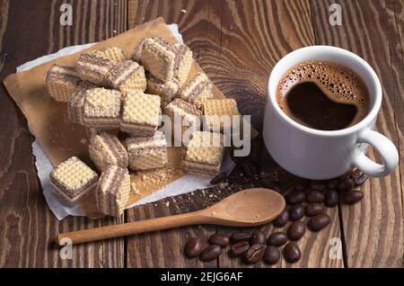 Tasse heißen Kaffee und kleine Schokoladenwaffeln auf alten Holztisch Stockfoto