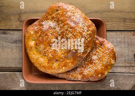 Hausgemachtes türkisches Pide-Brot, das mit Eigelb und Sesam glasiert wurde, auf einem hölzernen Hintergrund. England GB Stockfoto