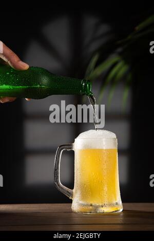 Frisches Bier in Bierkrug auf Holzsockel gegossen. Vertikales Format. Stockfoto