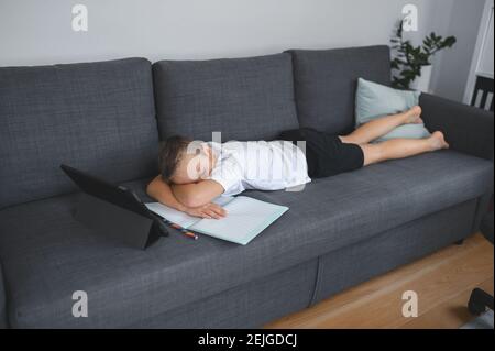 Online-Bildung, Homeschooling. Schuljunge mit Online-Unterricht zu Hause auf dem Trainer Stockfoto