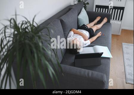 Online-Bildung, Homeschooling. Schuljunge mit Online-Unterricht zu Hause auf dem Trainer Stockfoto