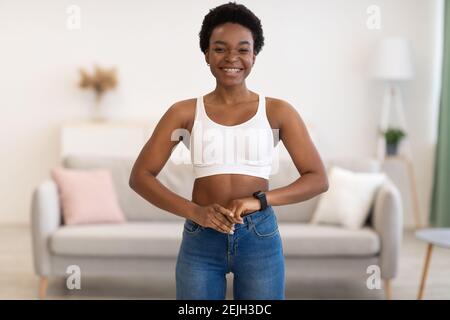 Happy African Lady Trägt Skinny Jeans Nach Dem Abnehmen Zu Hause Stockfoto