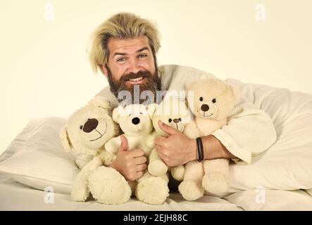 Bemühen Sie sich, gute Schlafgewohnheiten zu üben. Niedliches Teddybär Spielzeug. Positive Schlafzimmer Umgebung. Verspielt und romantisch. Bärtiger Hipster Spielzeug spielen. Mann umarmen Spielzeug im Bett entspannen. Gute Stimmung. Imaginäre Freunde. Stockfoto