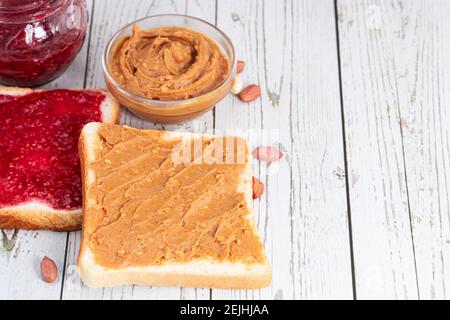 Toasts mit Erdnussbutter und Beerenmarmelade auf hellem Holzhintergrund. Stockfoto